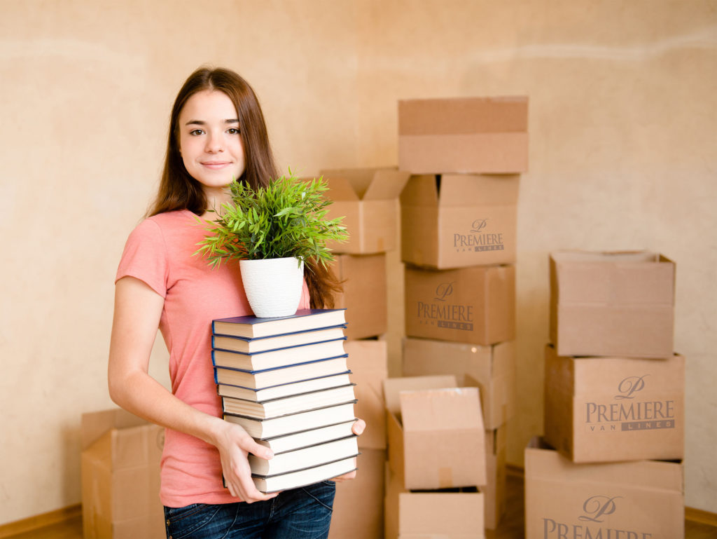Girl holding stack of books while moving