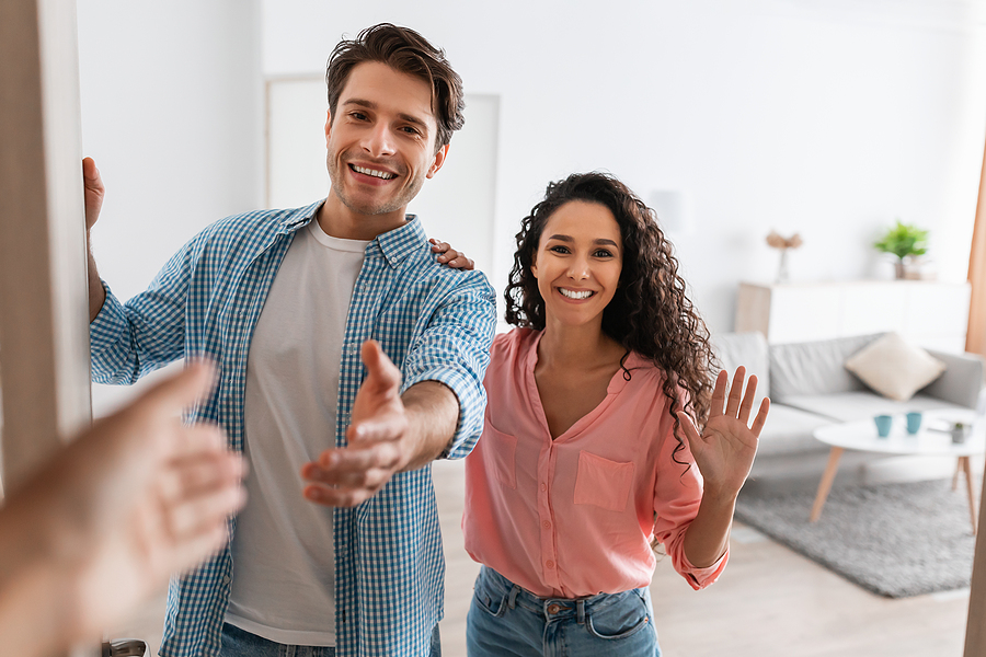 Young couple welcoming people to their new home